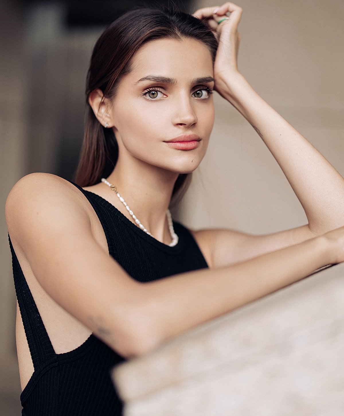 Woman in elegant attire, posing thoughtfully.