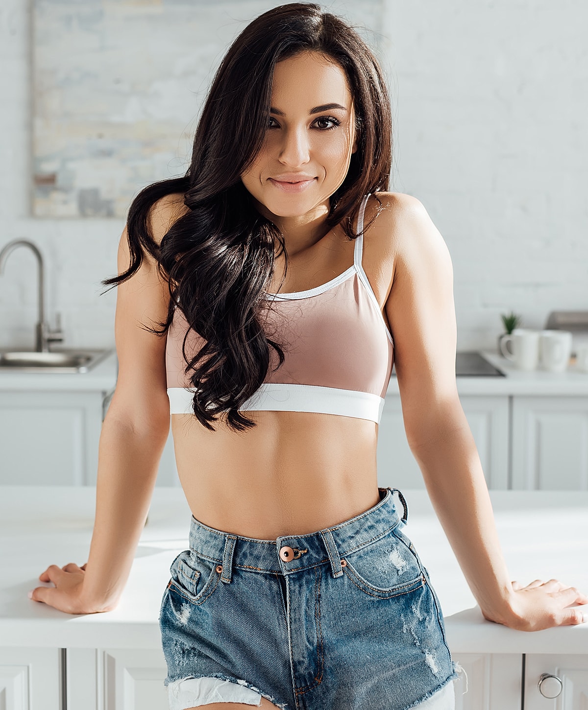 Woman posing in casual attire in kitchen.