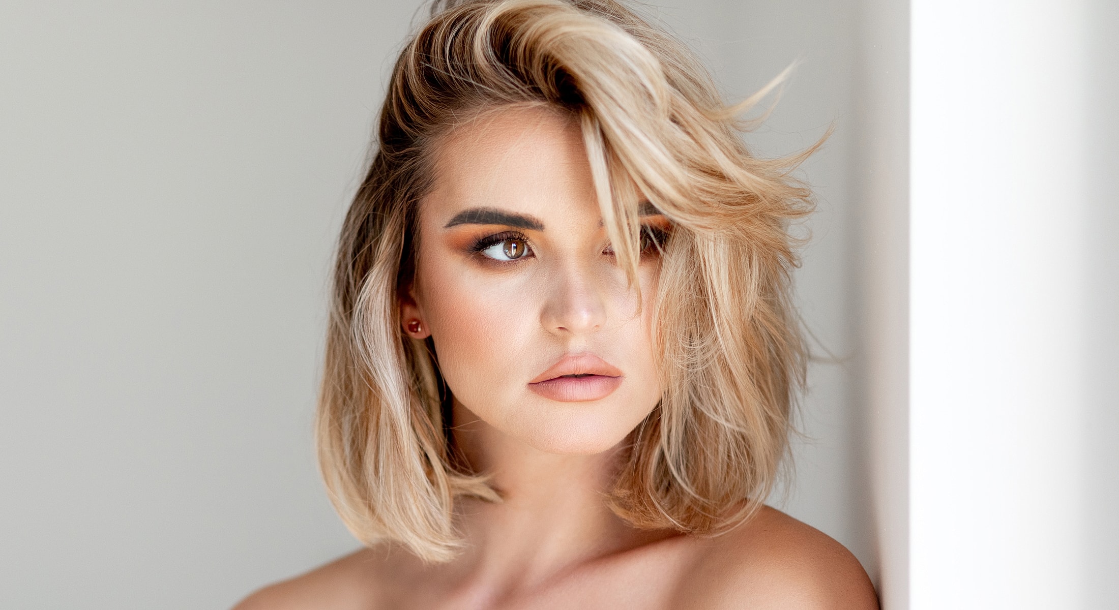 Woman with stylish blonde bob hairstyle and makeup.