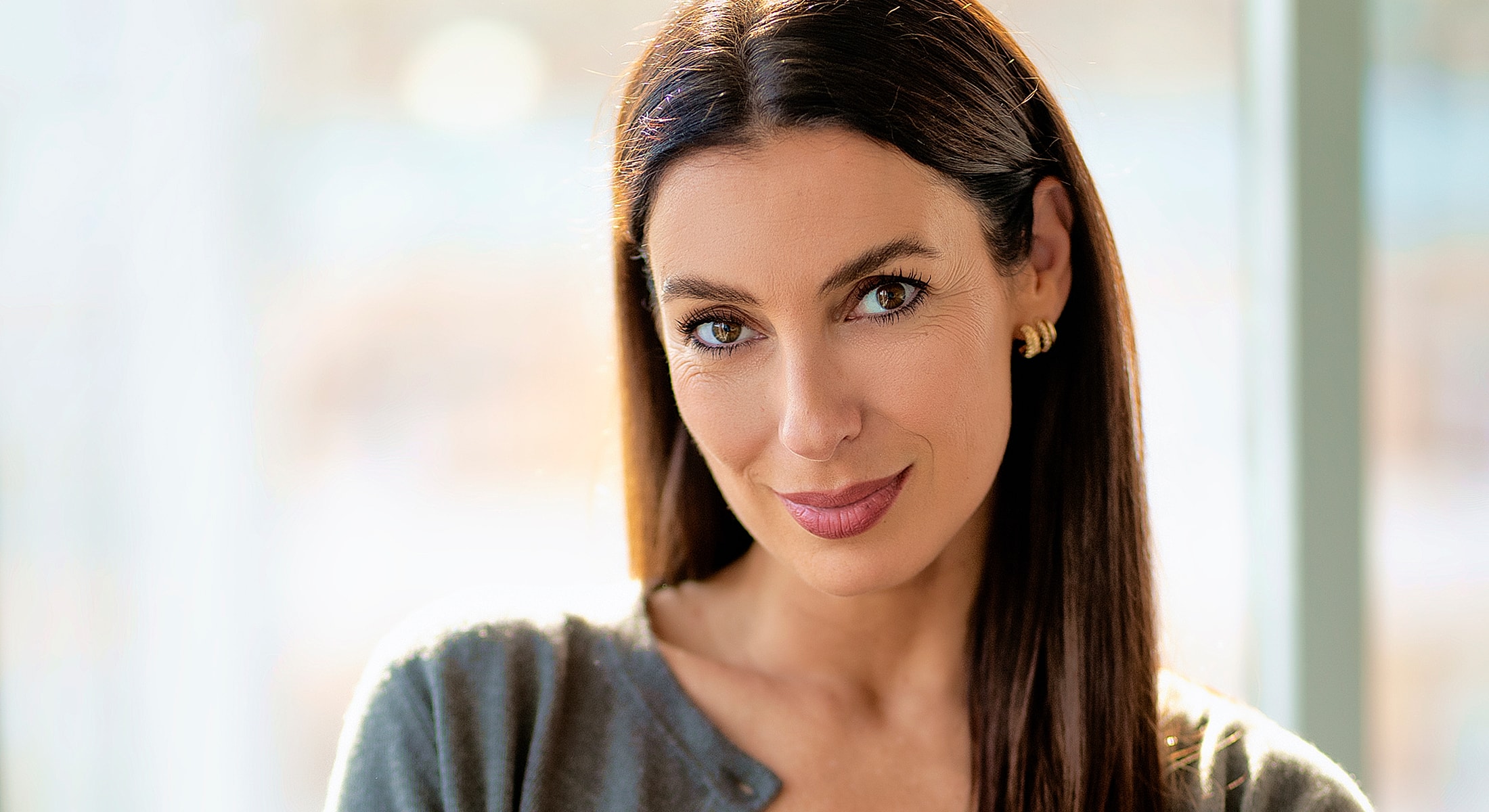Smiling woman in soft lighting, casual clothing.